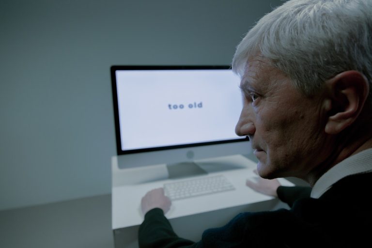 Elderly man using a computer, with the screen displaying the words "too old", symbolizing challenges faced by older employees in the workplace, highlighting the importance of private investigators in addressing insider threats in Mexican businesses.